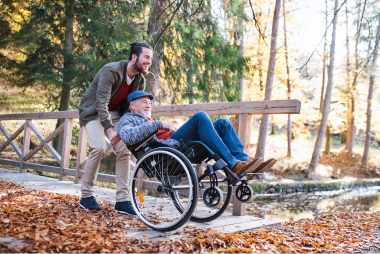 Homme qui pousse un home agé en fauteuil roulant