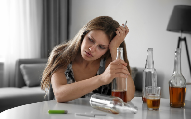 Femme qui fume avec des verres d'alcool